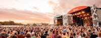 a crowd of people at a music festival at sunset